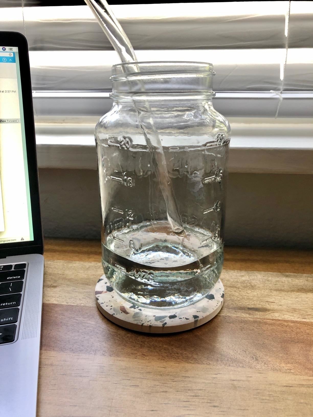 a terrazzo-patterned coaster sitting next to a reviewer's laptop