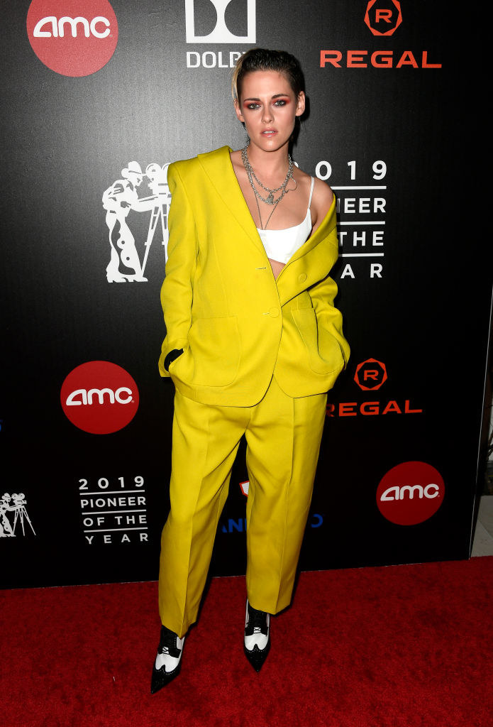 a brightly colored oversized suit jacket and trousers worn with a bralette and pointy shoes