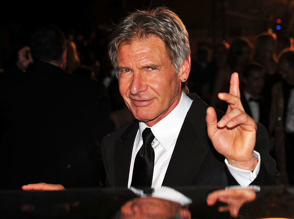 Harrison smiling and pointing on a red carpet