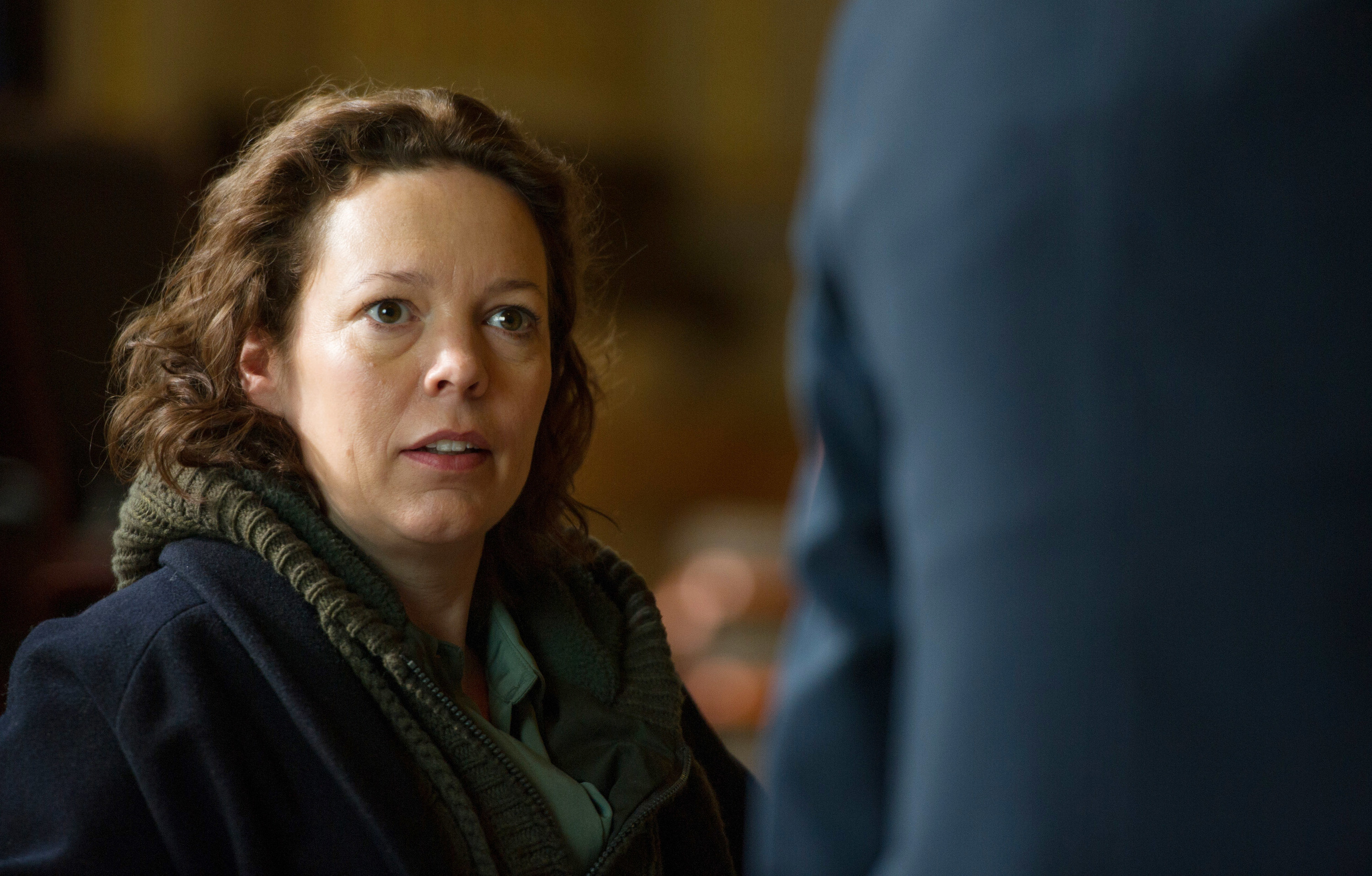 Olivia Colman sitting and looking concerned.