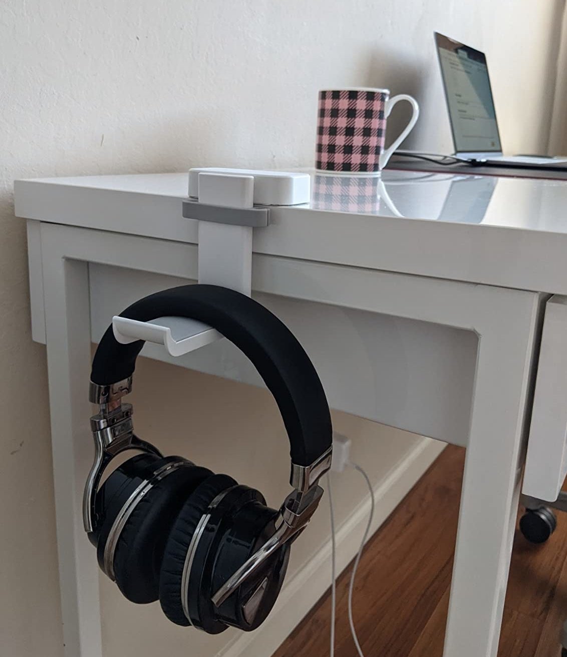 a reviewer shows the white headphone holder attached to a desk