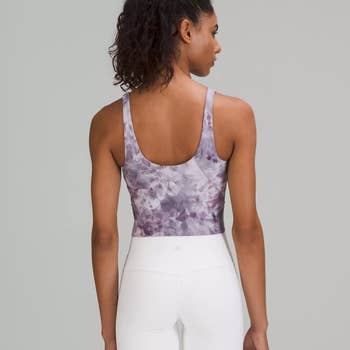 A model wearing the same athletic tank top in lavender tie dye
