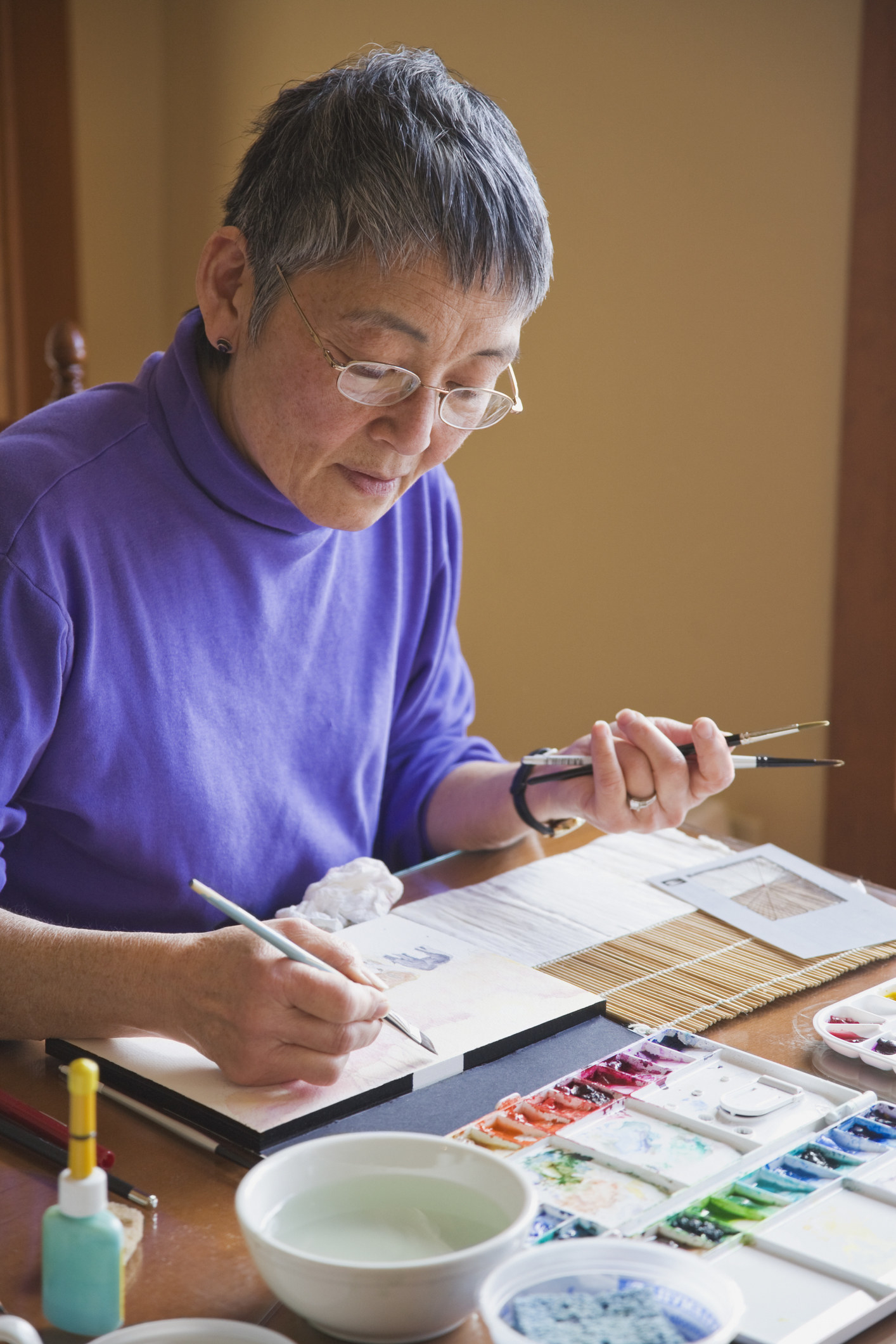 Older woman painting with watercolors at a table