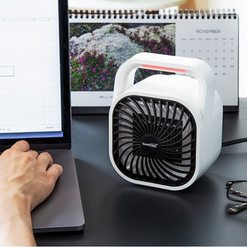 a white heater sitting beside a laptop
