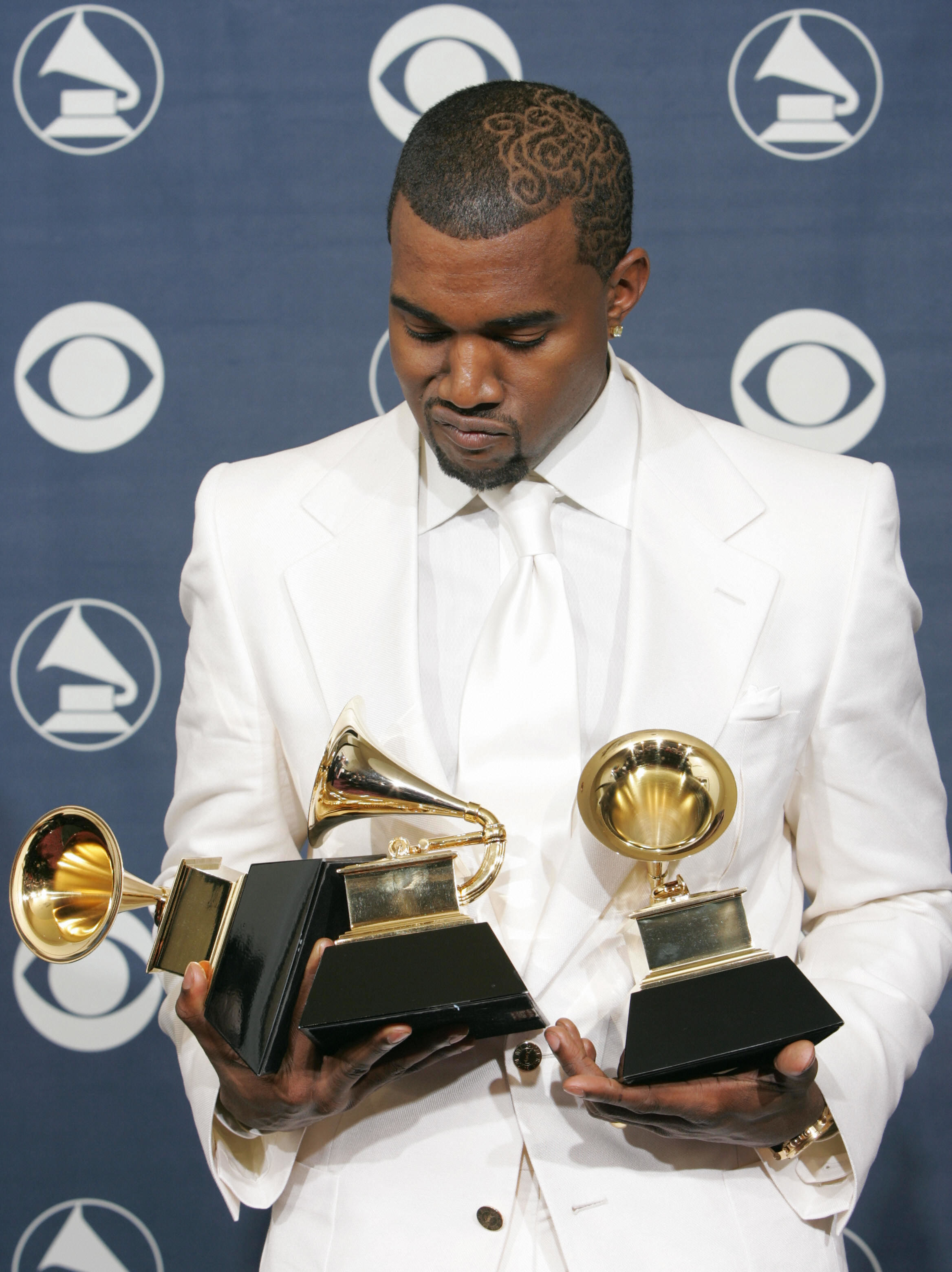 US rapper Kanye West looks down at his three Grammys February 13, 2005, after the Grammy Awards ceremony in Los Angeles
