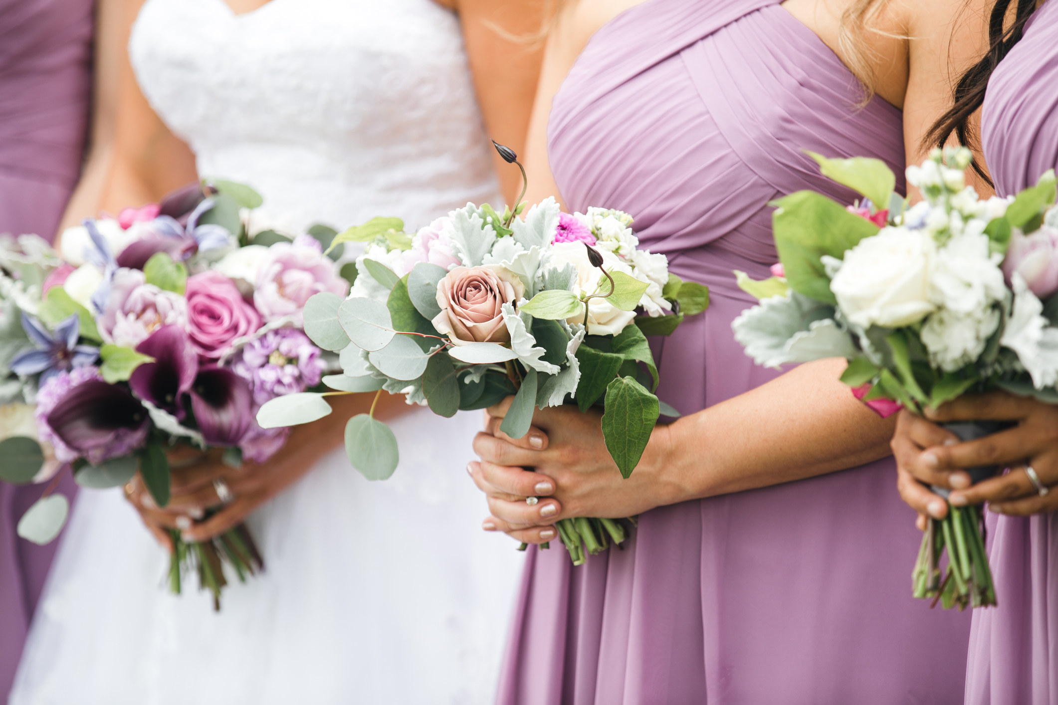 Three bridesmaids in between the bride, each holding a bouquet