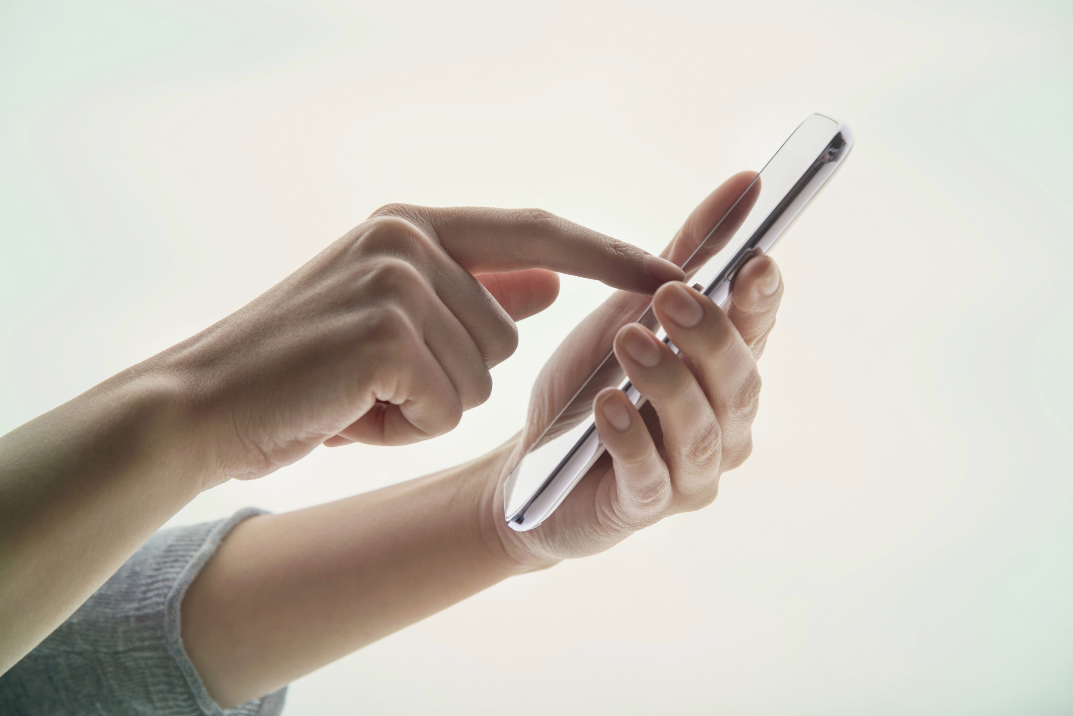 Young woman&#x27;s hands using a portable information device on white background