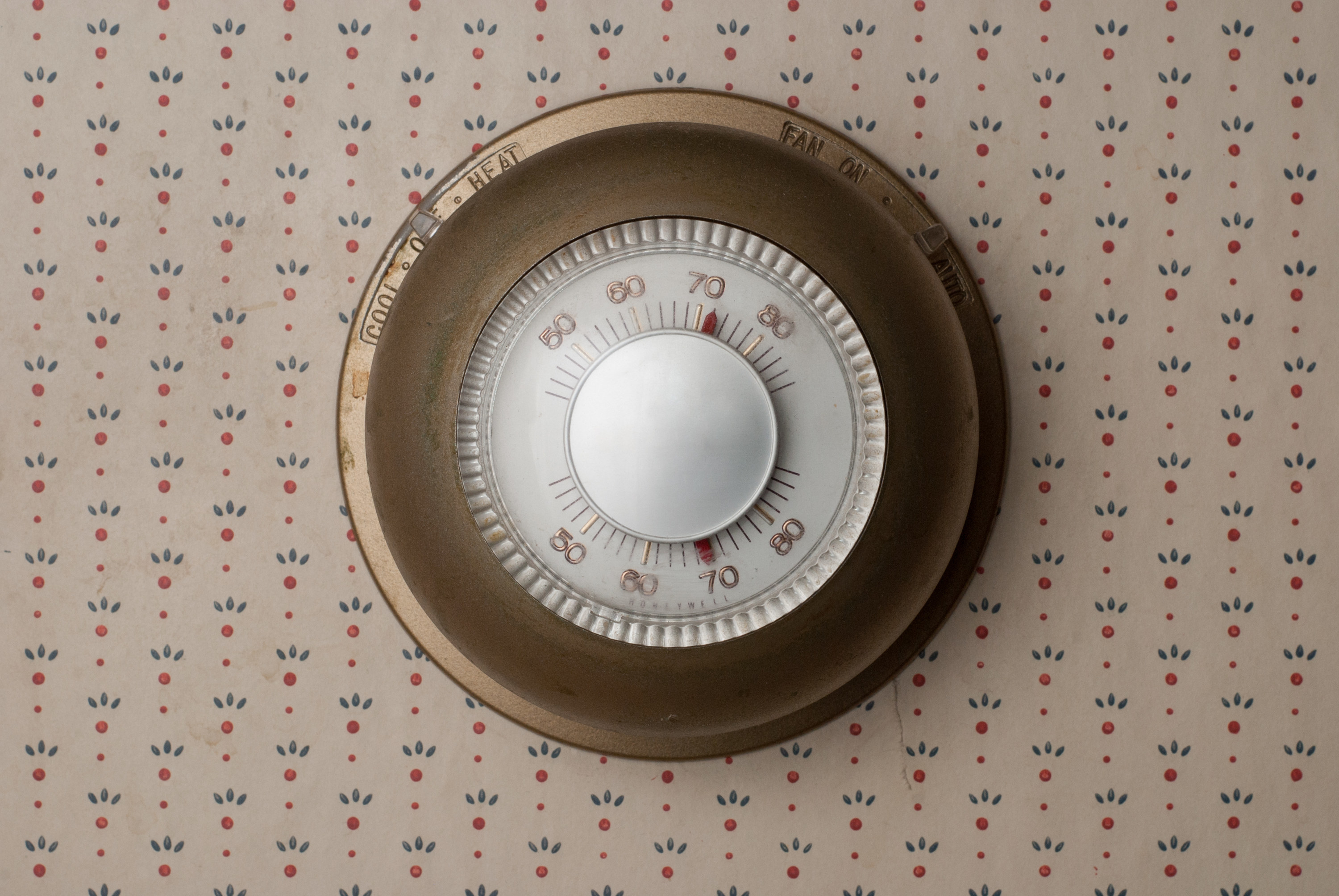 Old fashioned, outdated thermostat on old wallpaper