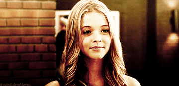 Alison from Pretty Little liars smiling and winking as people walk past behind her