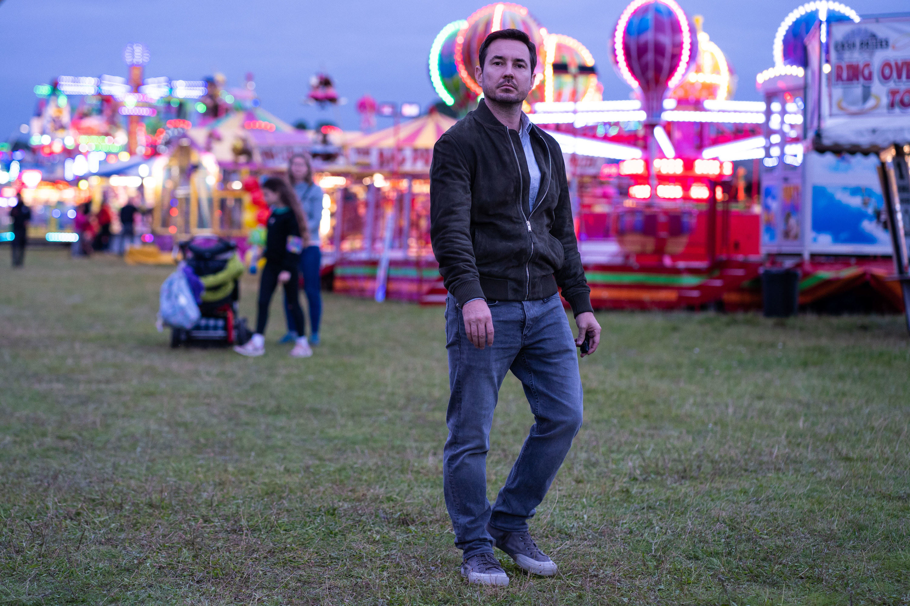 Martin Compston as Bram Lawson walking through a carnival alone