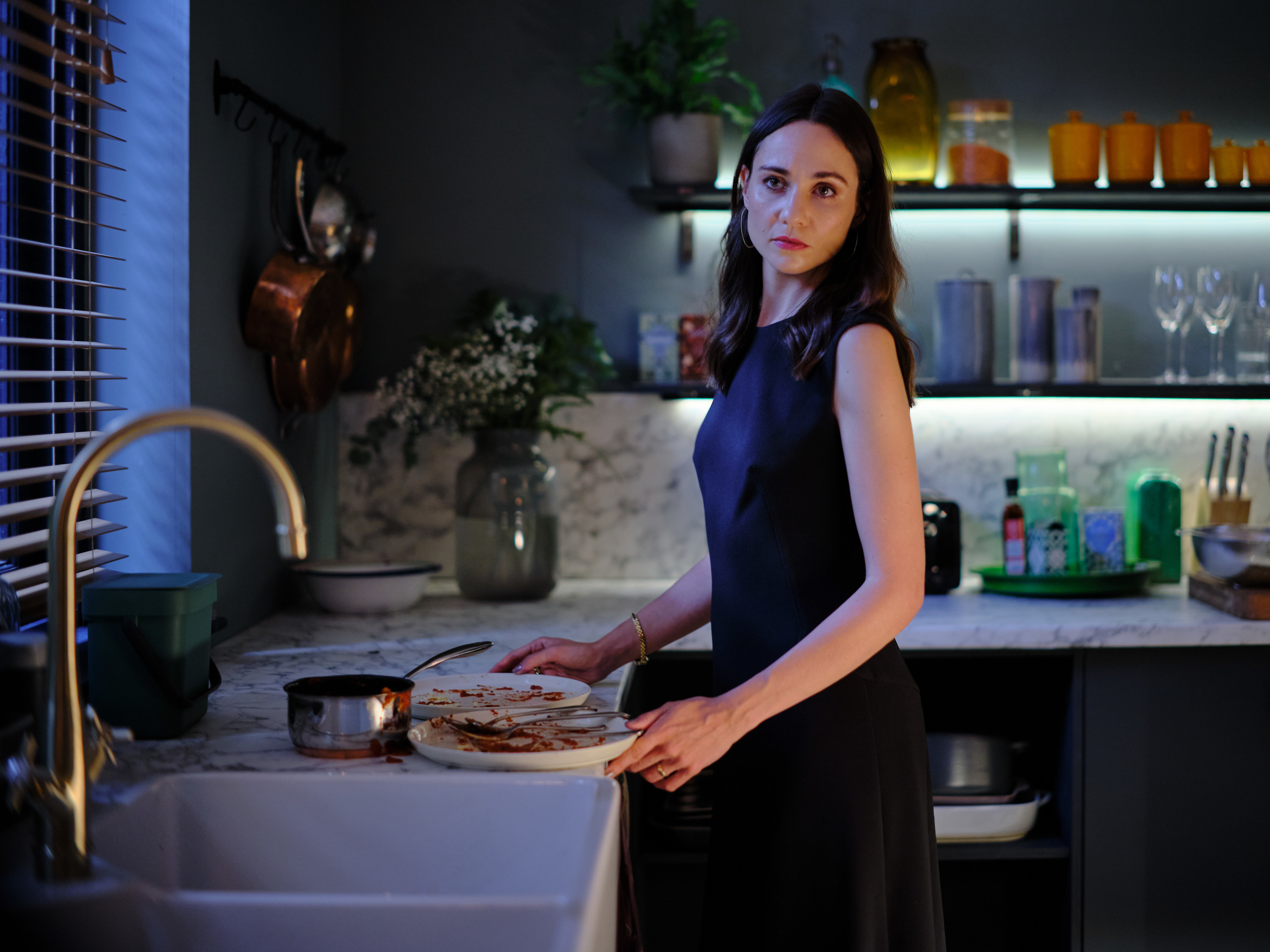 Tuppence Middleton as Fi Lawson putting dirty dishes down by the kitchen sink