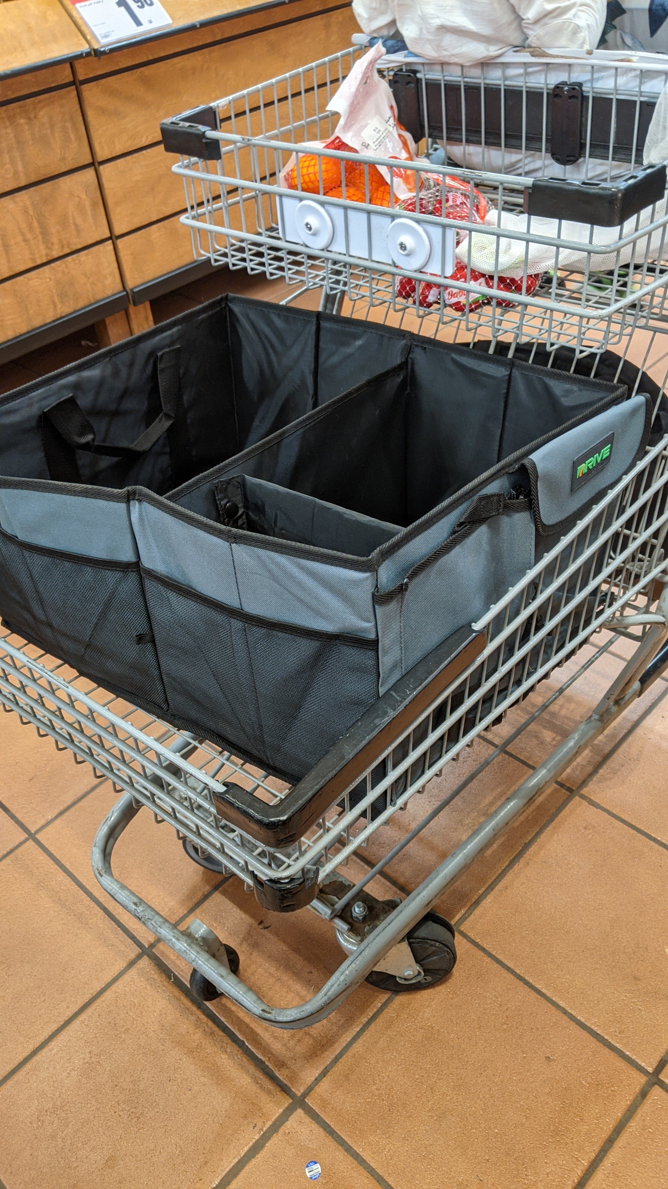 A shopping cart with a large fabric box filled with groceries in the bottom basket