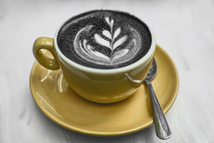 A charcoal latte with latte art in it