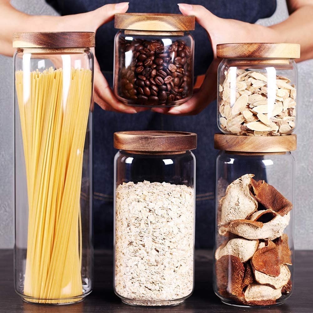a set of glass stacking canisters filled with dry pantry goods