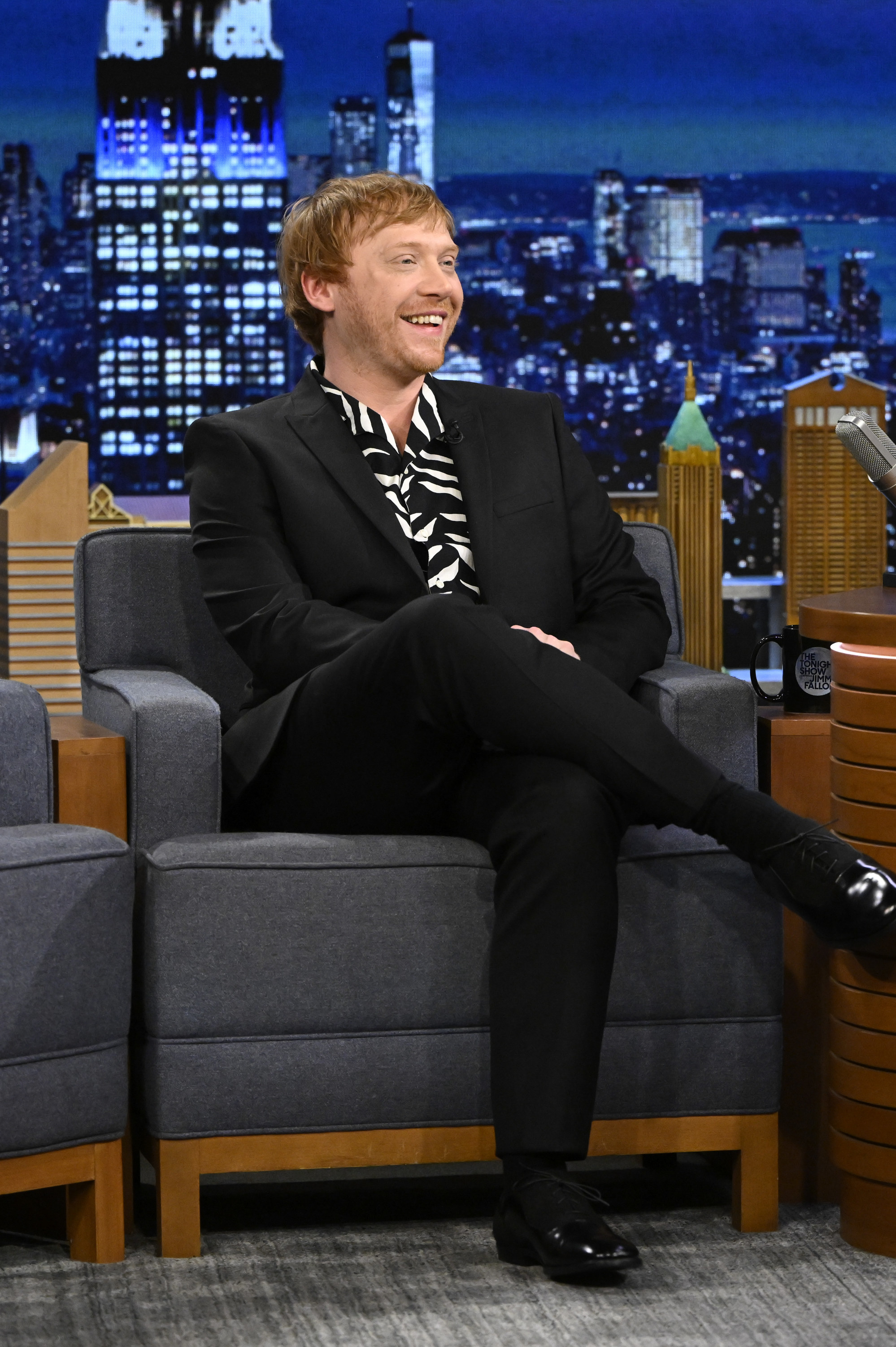 Rupert smiling in a chair during a talk show interview