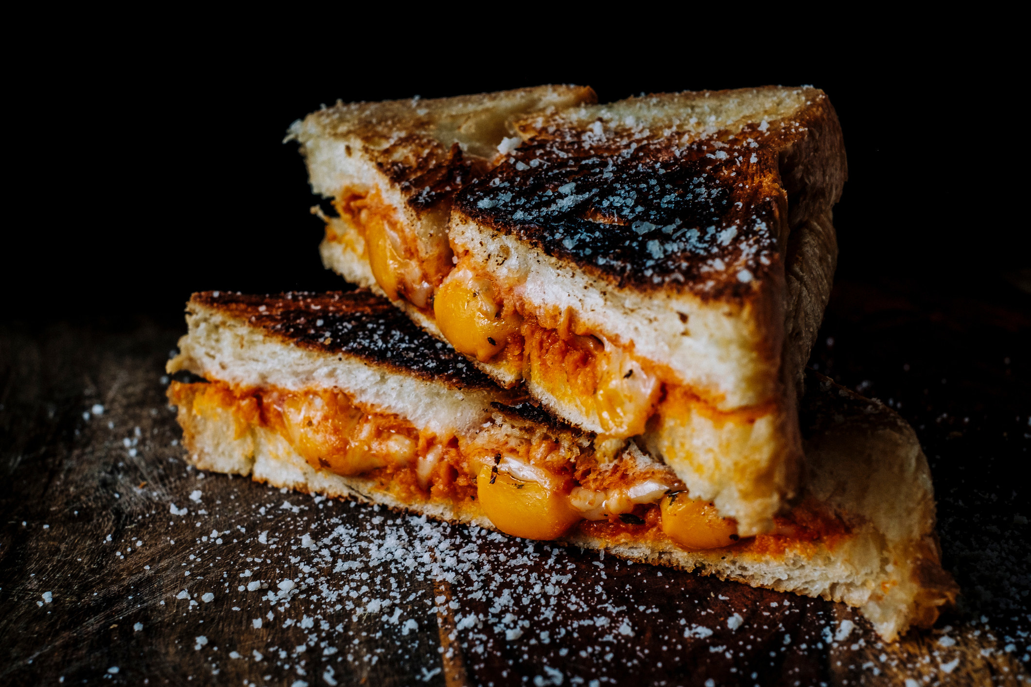 A charred grilled cheese sandwich with salt sprinkled on top
