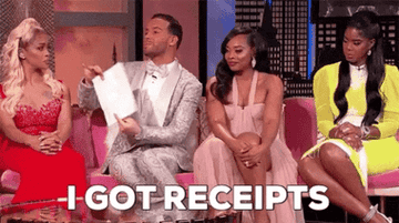 A person sitting on a couch with other people holding a piece of paper with the text, &quot;I got receipts&quot;