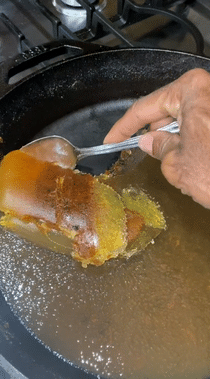 gif of reviewer using a spoon to remove the oil from a pan