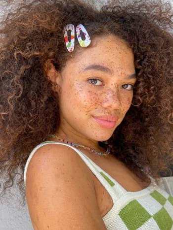 a model with curly hair wears two clips in the front of her head