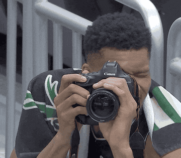 a gif of a Milwaukee Bucks basketball player taking a photo, looking at the camera screen, and then giving a thumbs up