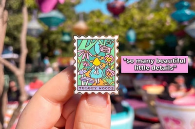 a model holding a stamp-shaped pin with an alice in wonderland design