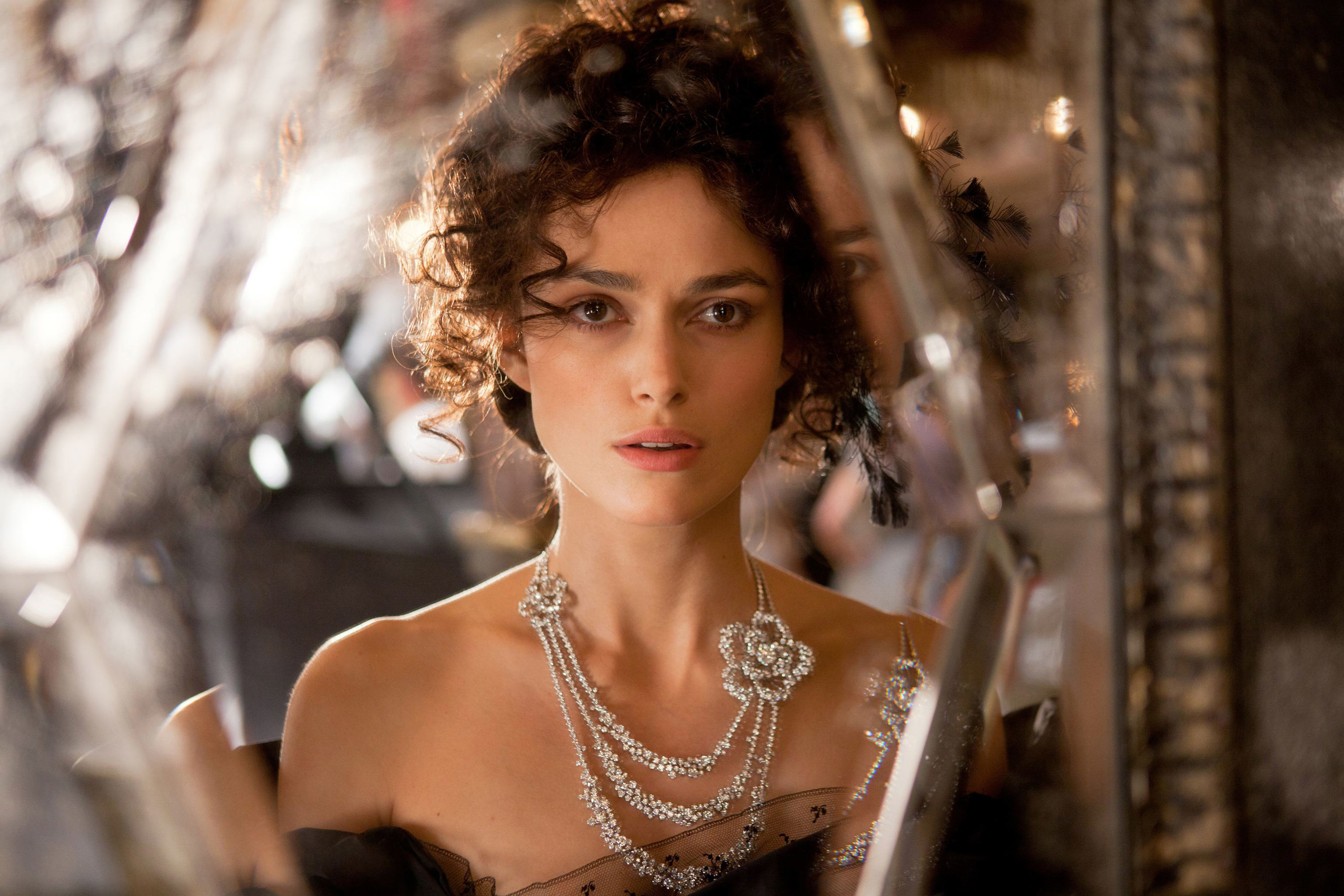 Keira wearing an ornate diamond necklace that has three chains of diamonds and flower designs