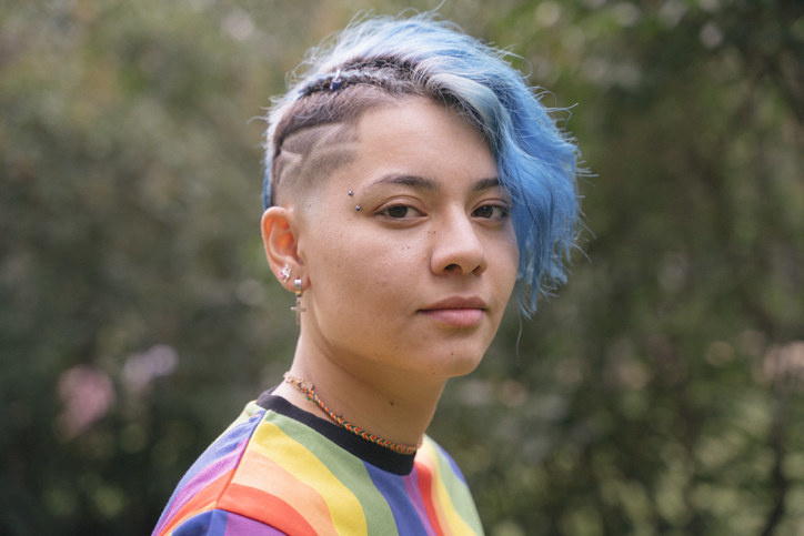 Person with blue hair and a rainbow shirt
