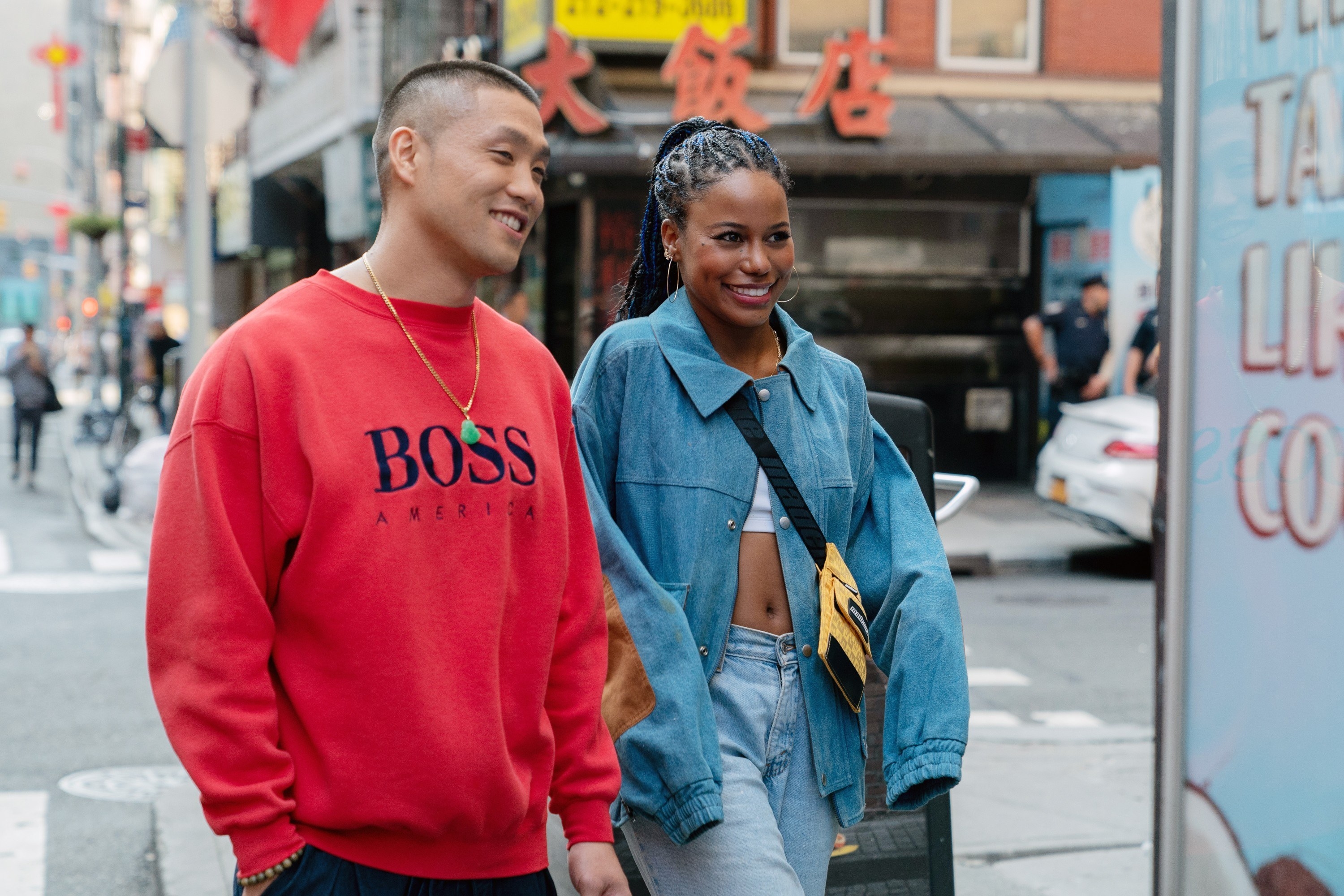 Taylor Takahashi in a red sweatshirt and Taylour Paige in a jean jacket smiling and walking down a street in NY