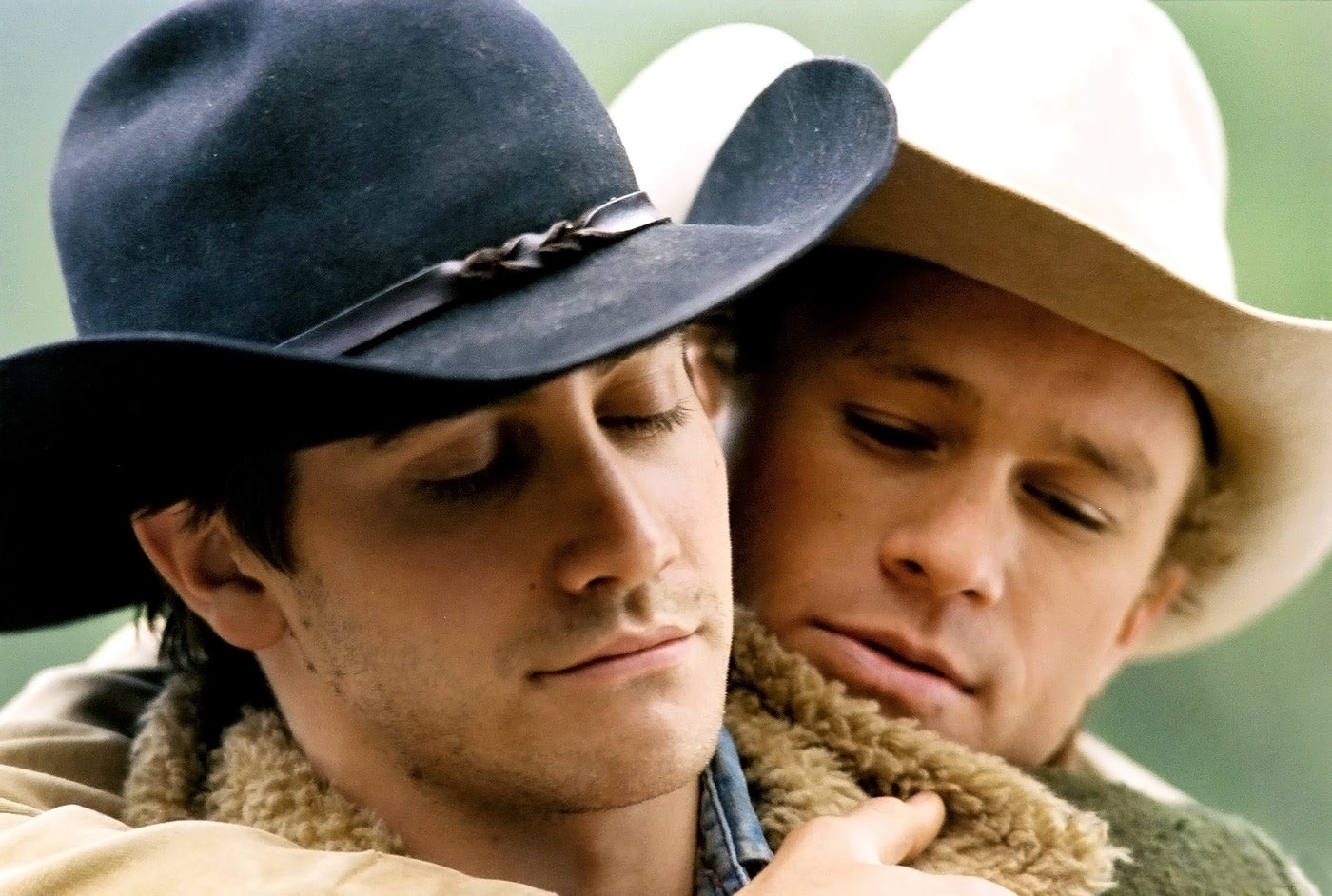 Heath Ledger hugging Jake Gyllenaal from behind, both wearing cowboy hats