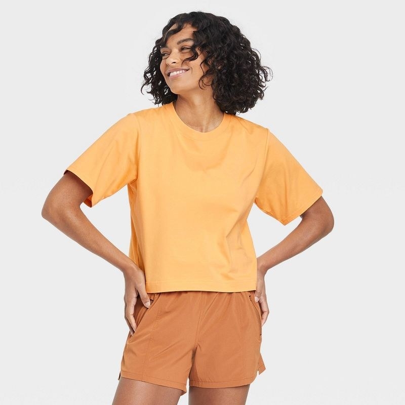 Model wearing the peach orange cropped cotton short-sleeve top