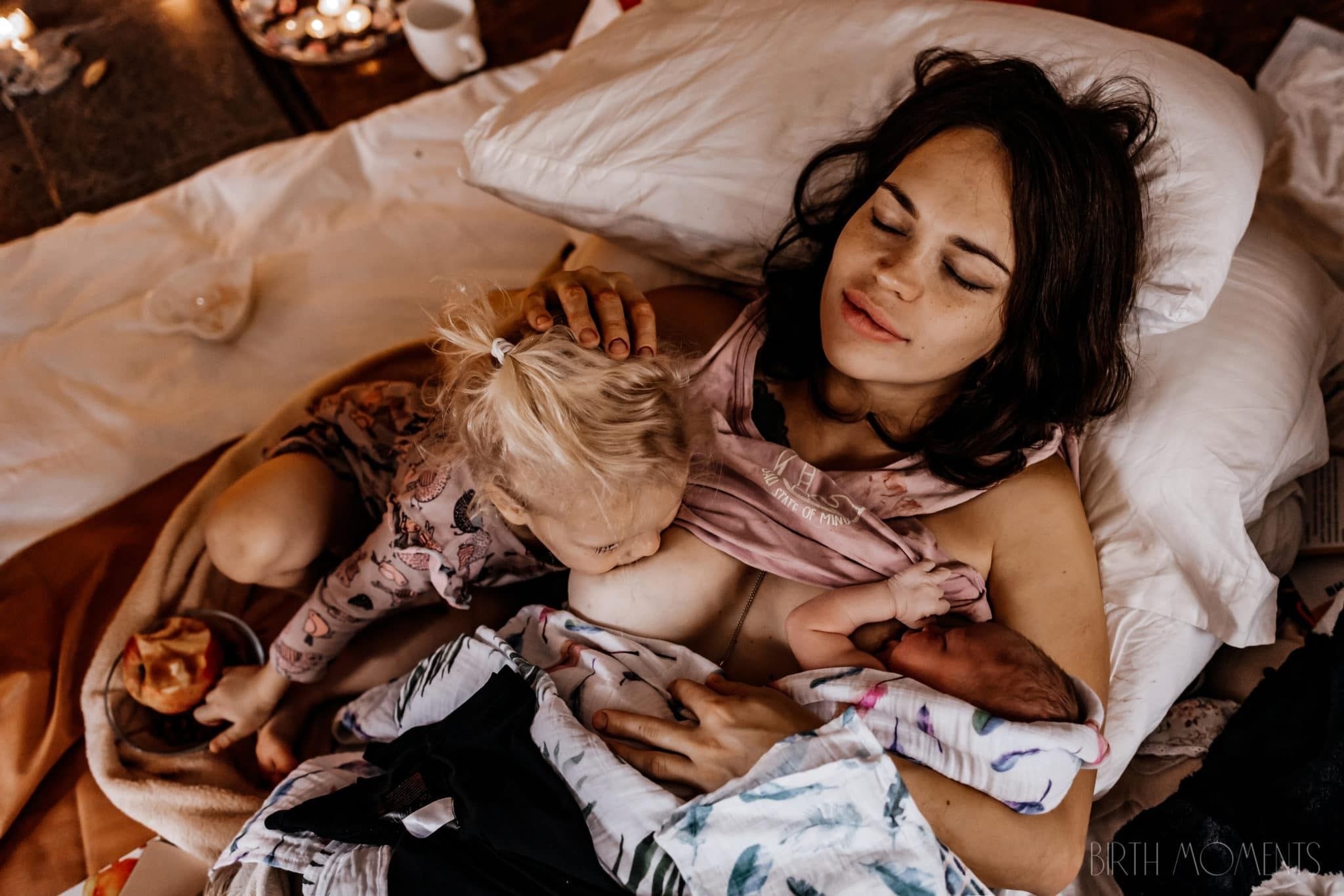 A woman breastfeeds her toddler and new baby