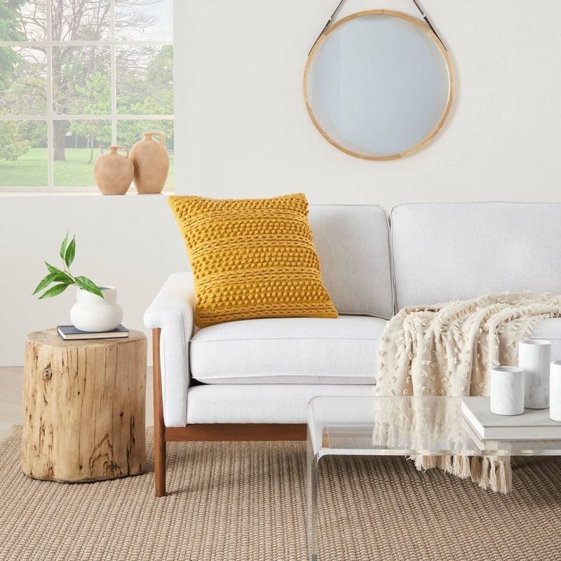 a woven pillow and throw pillow on a couch