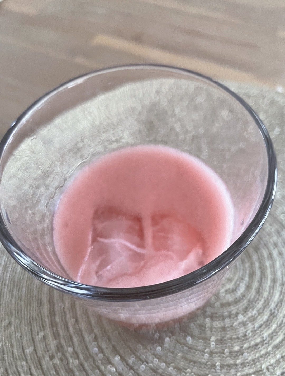 A top-down view of the liquid in the glass, showing a layer of pink fizz