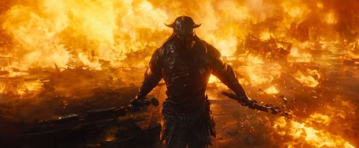 David Thewlis as Ares surrounded by fire, in his suit of armour