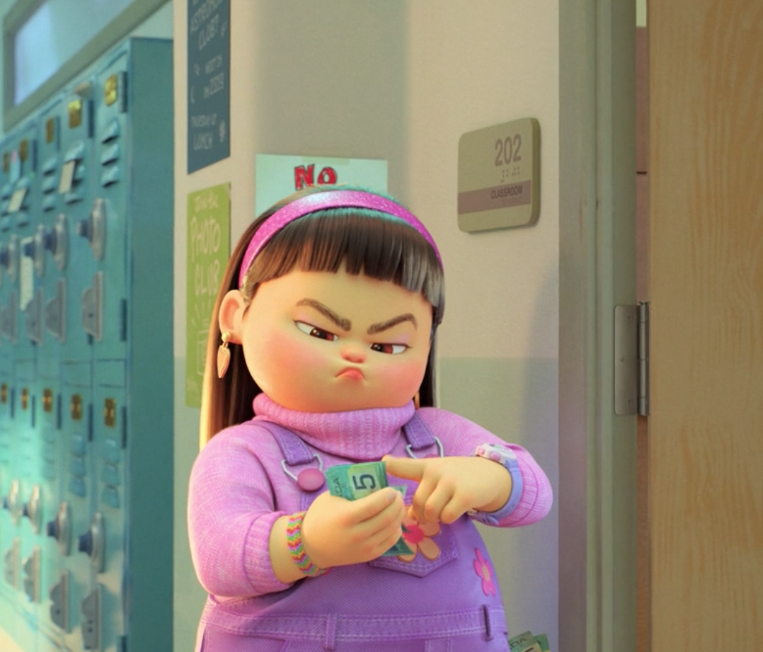 A still from the movie where a girl in and all-pink outfit is counting the money she has in her hand; she's standing in a school hallway near a door