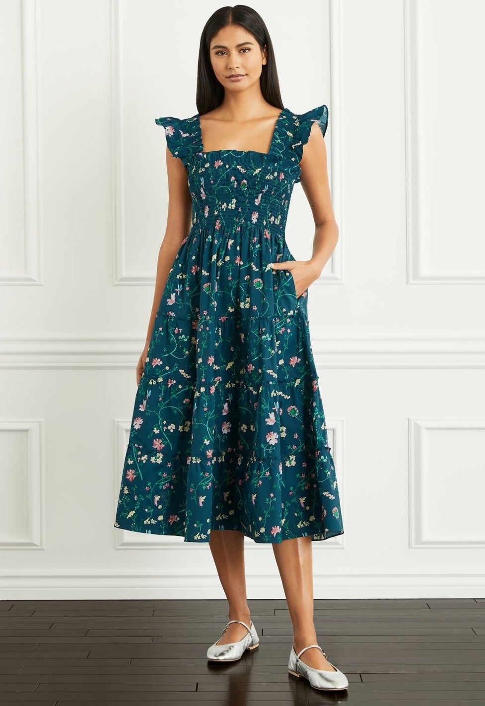 model in a teal floral pattern midi dress with a shirred top and flutter sleeves