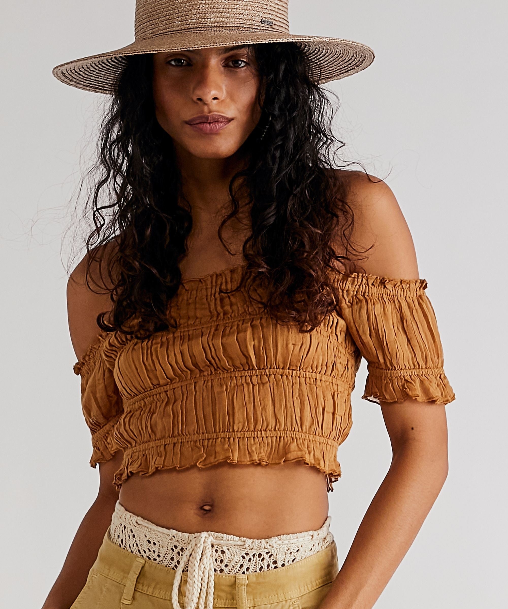 model in a burnt orange ruched crop top with off-the-shoulder short sleeves