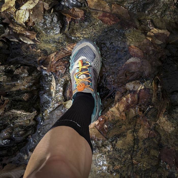 A person wearing the laces in their shoes while walking on a rock
