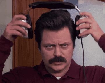 Nick Offerman as Ron Swanson in Parks and Rec puts a pair of headphones on his head