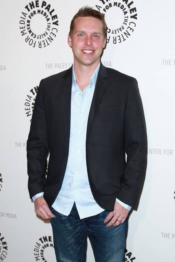 wearing an understated collared shirt, jacket, and jeans, Beigel smiles on the red carpet