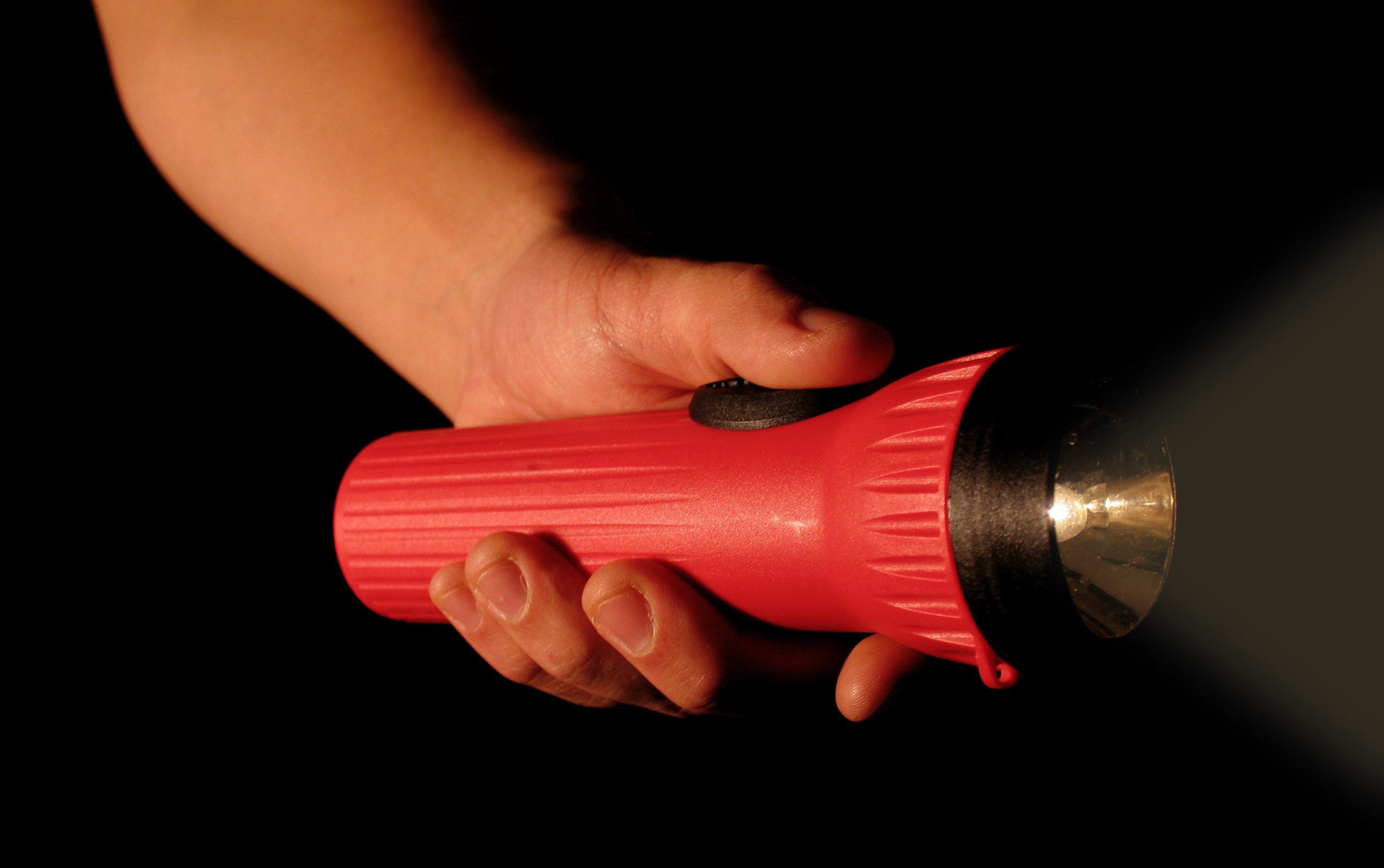 A hand holds a red flashlight