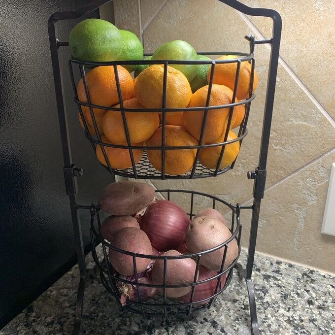 a reviewer photo of the double level fruit basket with fruit and vegetables inside