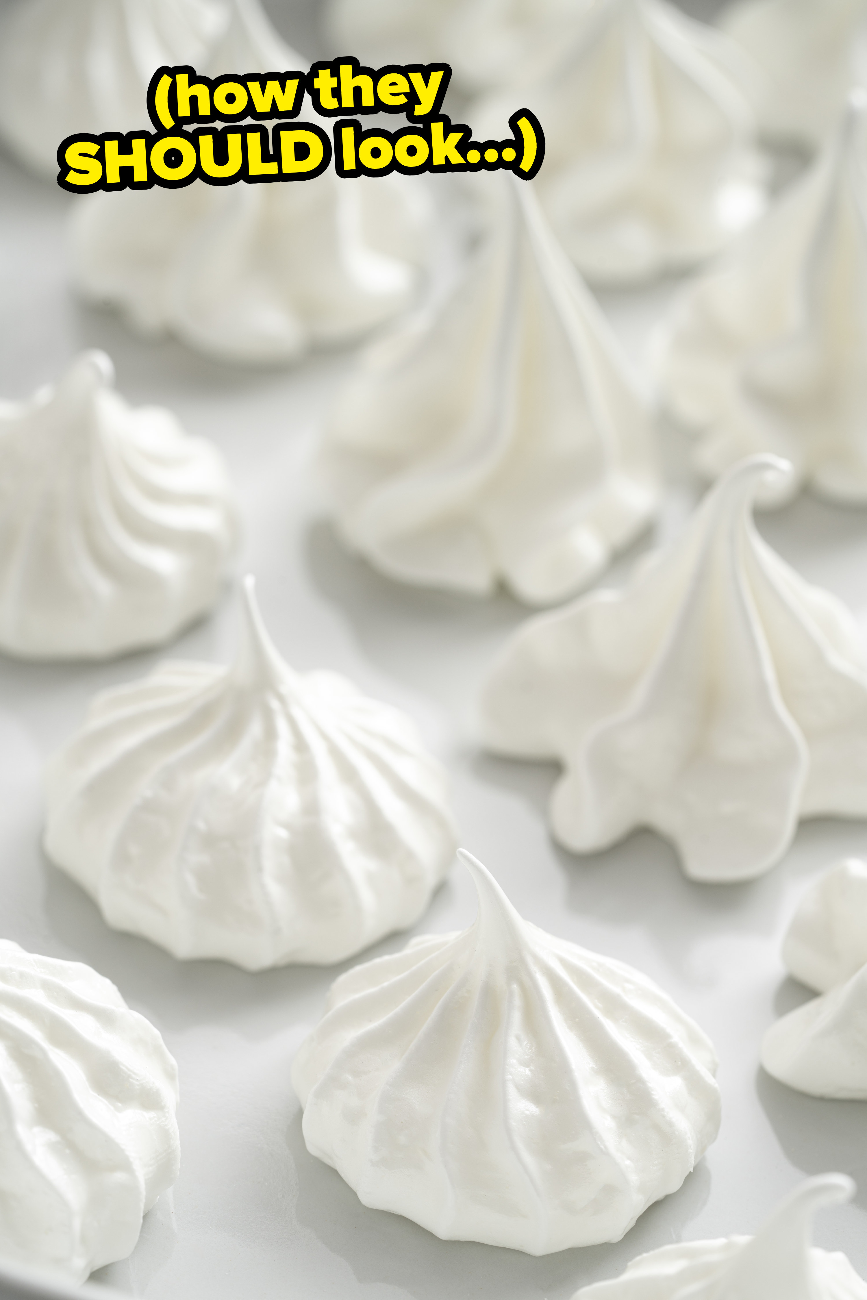 White meringues on a sheet tray with the text: &quot;How they SHOULD look&quot;