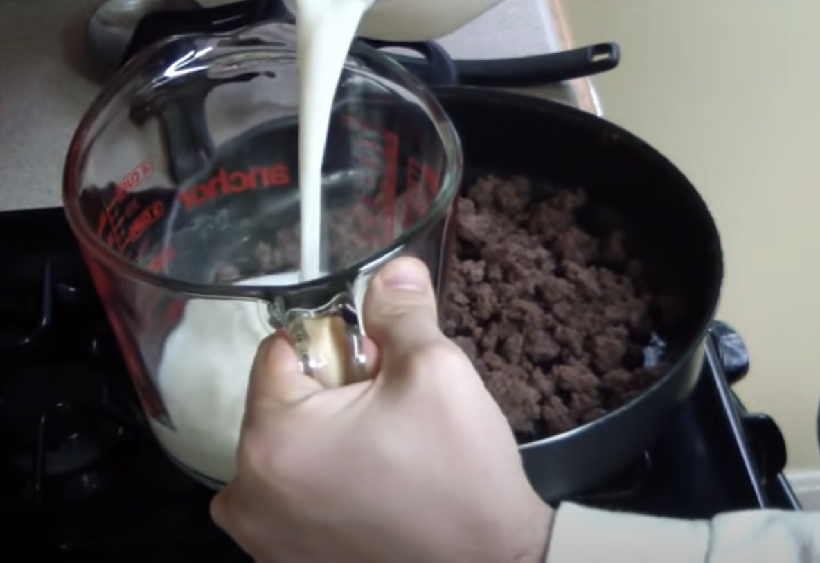 Pouring milk into a measuring cup before adding it to Hamburger Helper