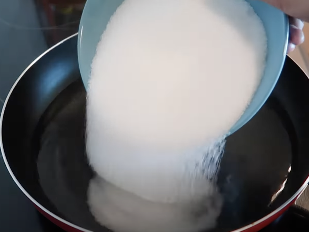 Pouring a white powdery substance into water on the stove