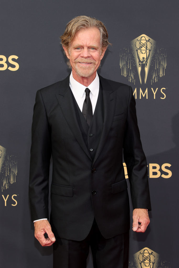 wearing a classic suit and tie, the actor smiles on the red carpet