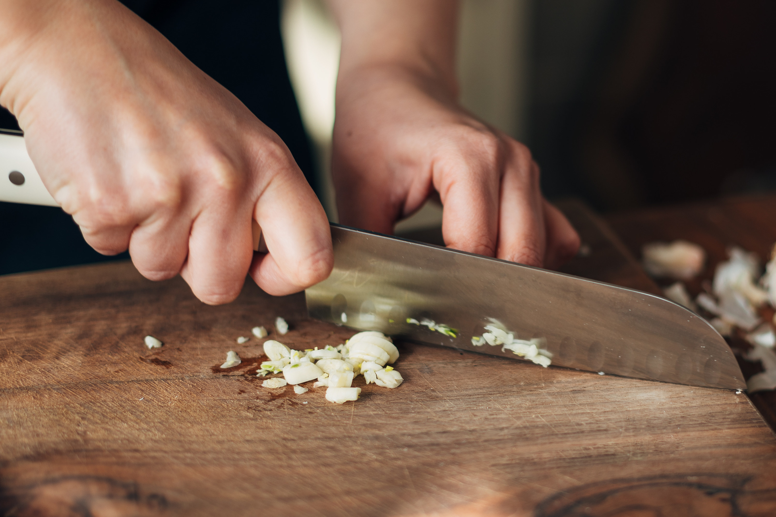 Chopping garlic on a wooden cutting board
