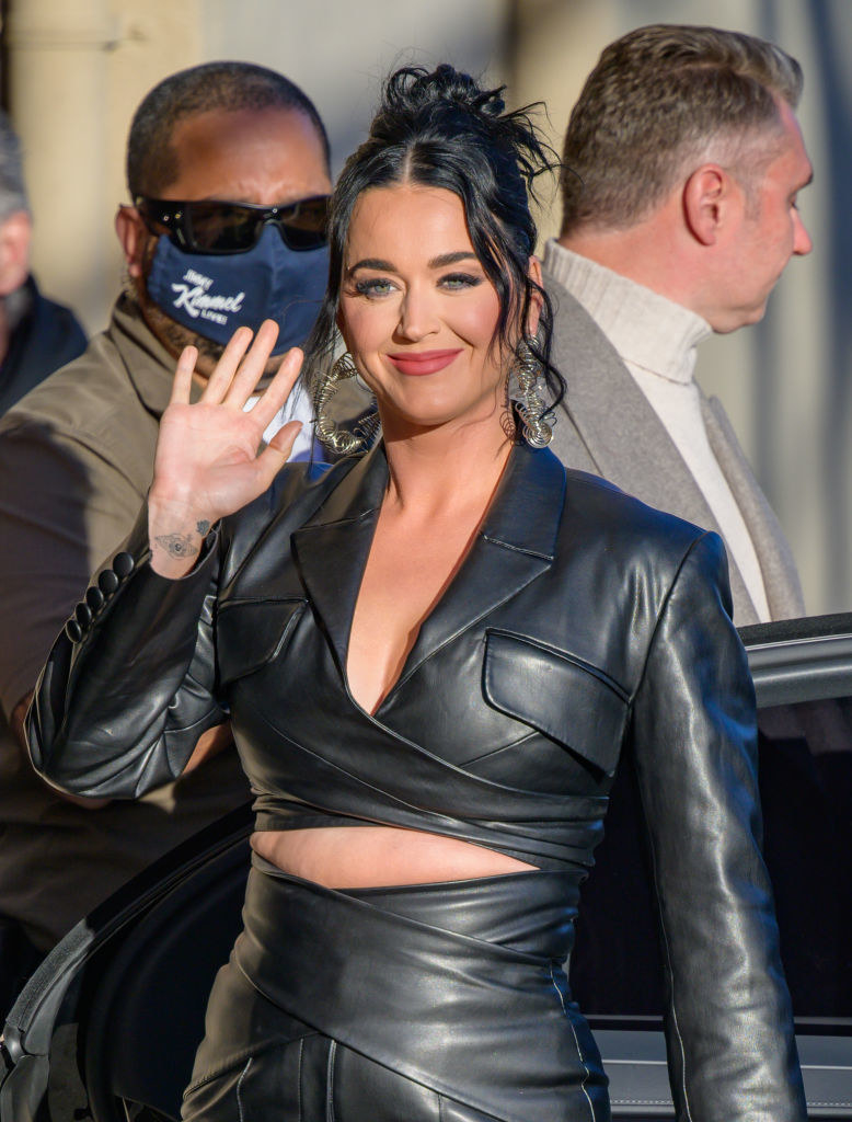 Katy Perry waves as she exits a vehicle in an all leather outfit