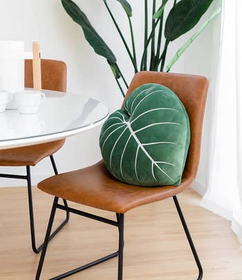 the green leaf-shaped pillow sitting on a dining room chair