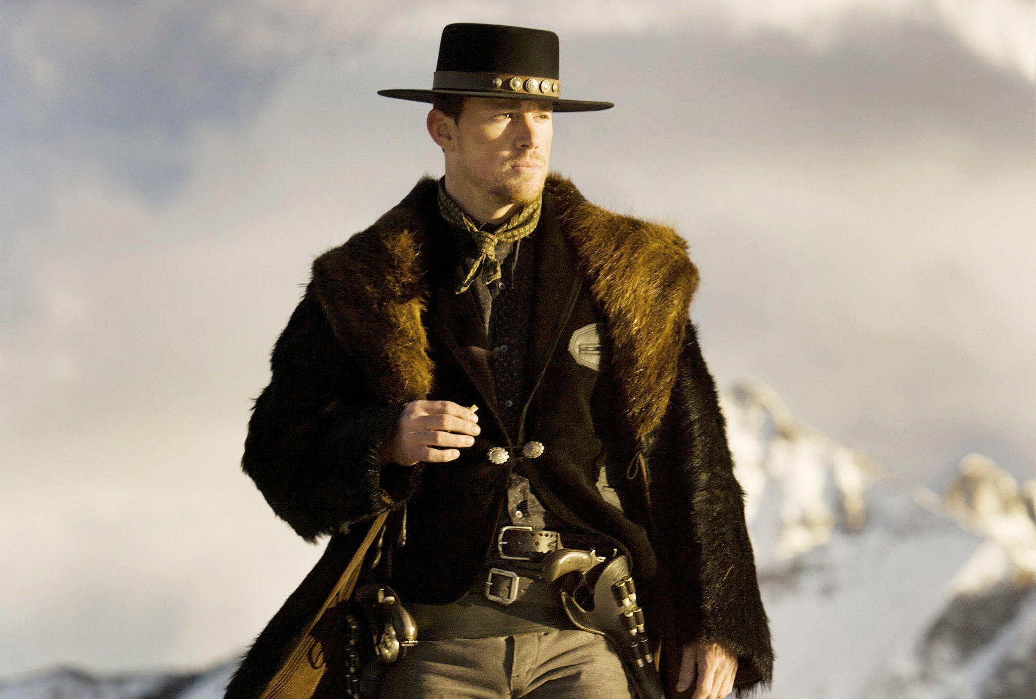 Tatum in front of snowy mountains wearing a fur coat and a wide-brimmed hat